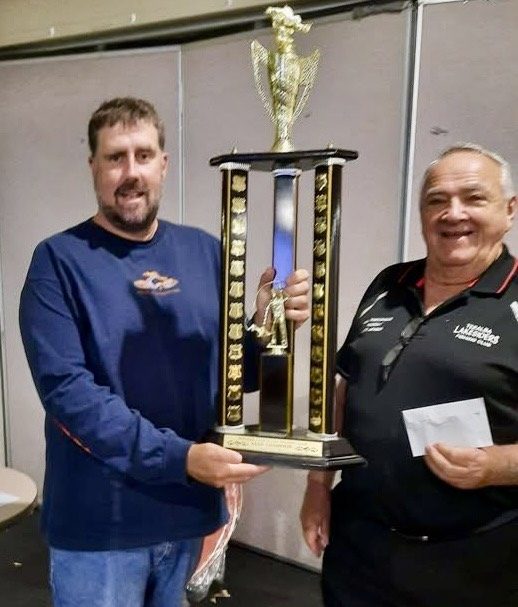 A member being presented with a tall champion angler trophy