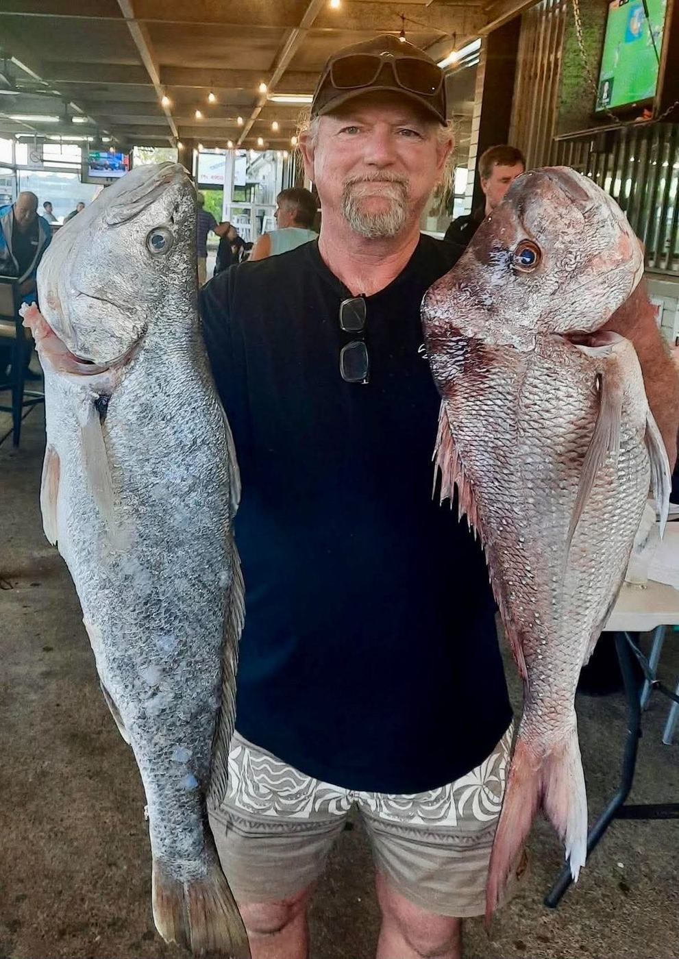 A club member holding up a mulloway and a snapper at the weigh-in