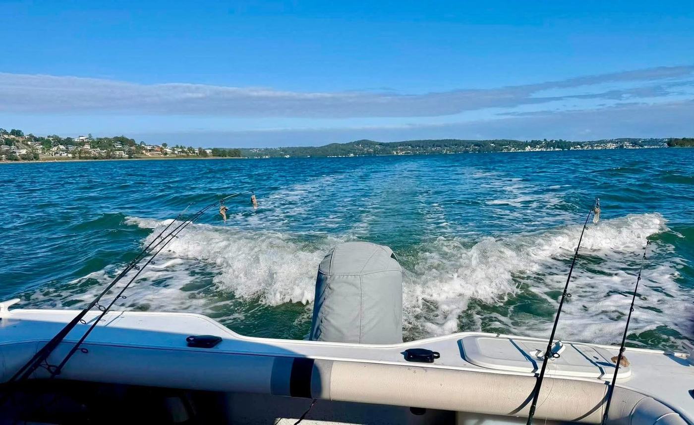 The wake behind a fishing boat crossing Lake Macquarie on a clear day, rods out