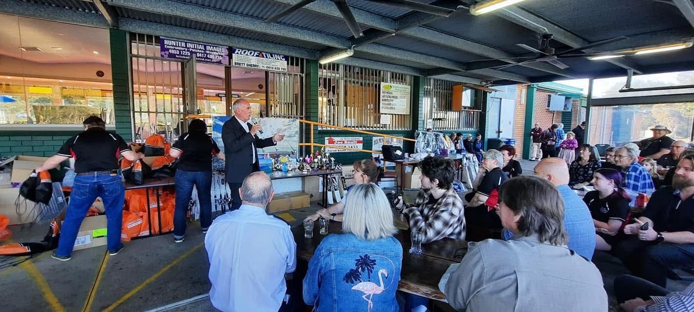 Members seated at tables while prizes and trophies are presented under the club awning