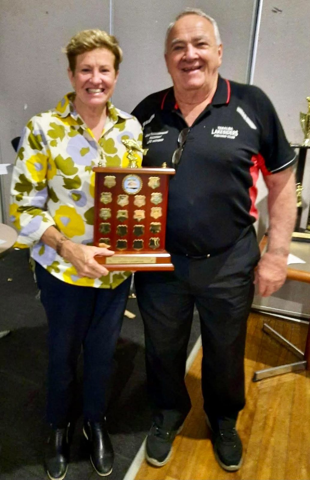 Two members holding a perpetual shield engraved with past champions