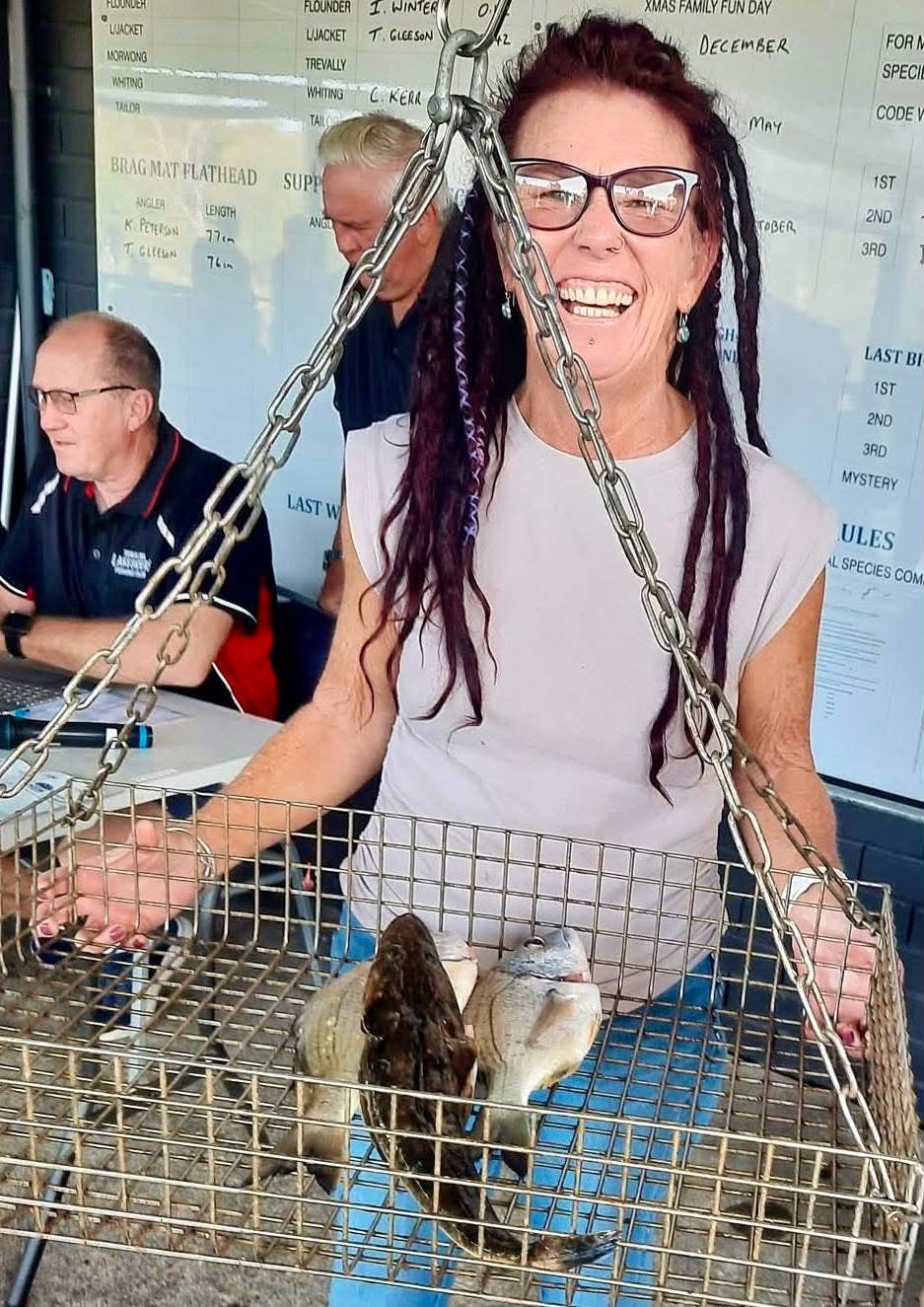 A woman angler laughing as she lifts her weigh-in basket